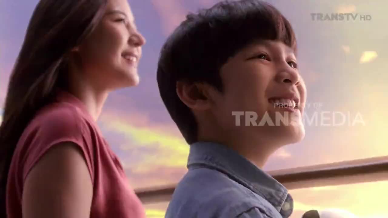 A young boy and a woman gaze upwards, their faces lit by a warm, golden light. The Trans TV logo is visible, suggesting this is a scene from a program broadcast in Indonesia.
