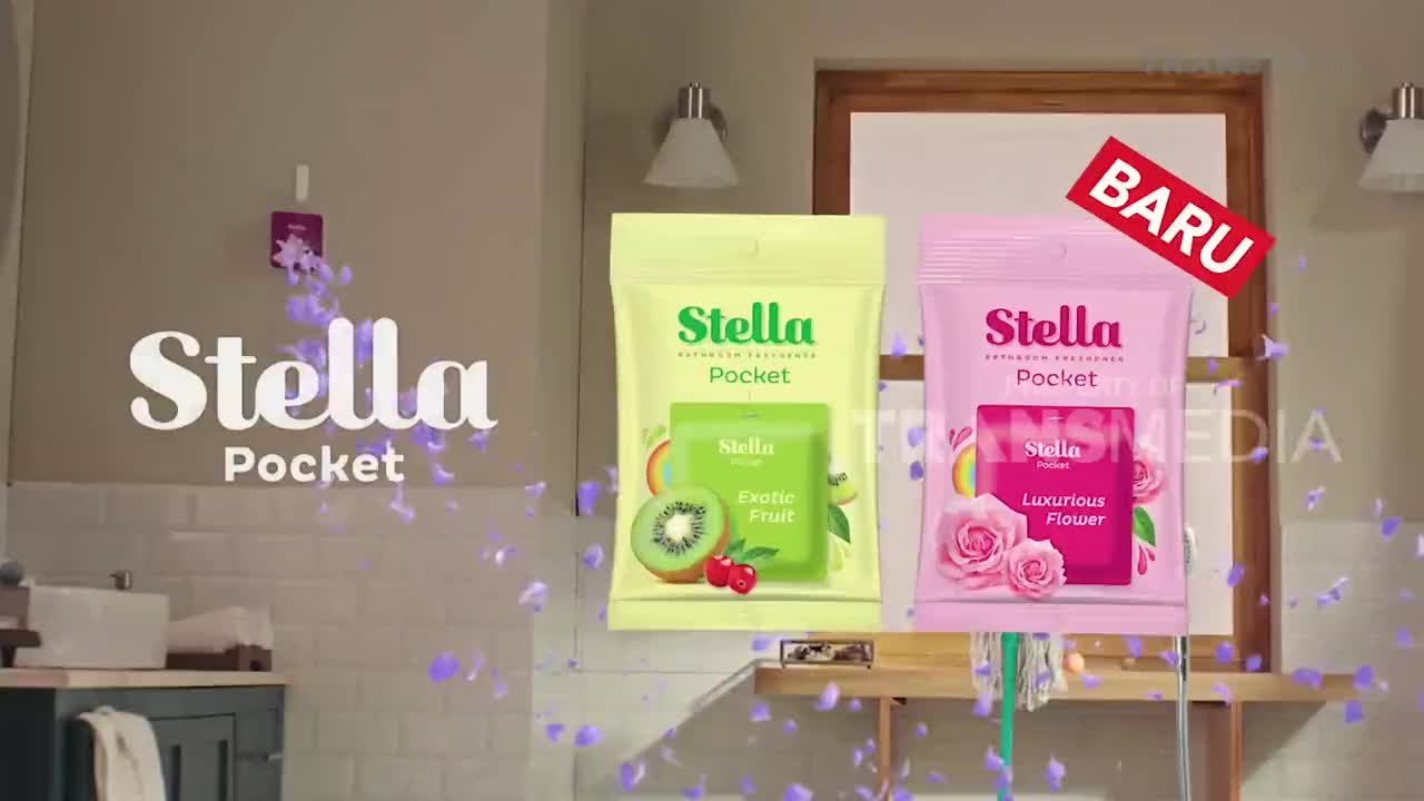 In a bathroom, two Stella Pocket air fresheners, one green and one pink, are prominently displayed.  Purple petals float around the Stella logo, as a "BARU" (new) banner appears above the pink packet, all part of a commercial on Trans TV.
