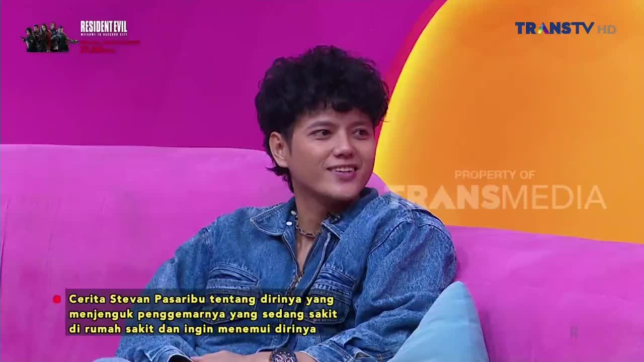 He's sitting on a pink couch, smiling while being interviewed on Trans TV. A caption at the bottom of the screen details the story Stevan Pasaribu is sharing.
