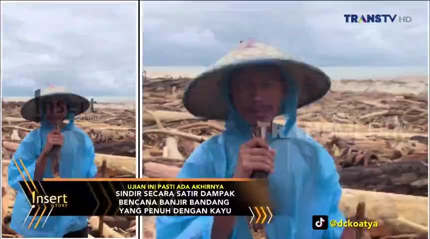 A man in a blue raincoat and a conical hat speaks into a microphone, standing in front of a beach covered in driftwood. The Trans TV logo is visible in the corner, and the scene is framed for a news report.
A man in a blue raincoat and a conical hat speaks into a microphone, standing in front of a beach covered in driftwood. The Trans TV logo is visible in the corner, and the scene is framed for a news report.