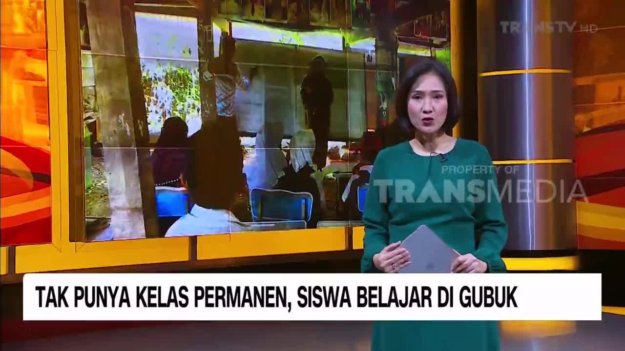 A news anchor, speaking for Trans TV, stands in a studio. Behind her, a screen shows a classroom in Indonesia, where students are studying in a makeshift structure.
A news anchor, speaking for Trans TV, stands in a studio. Behind her, a screen shows a classroom in Indonesia, where students are studying in a makeshift structure.