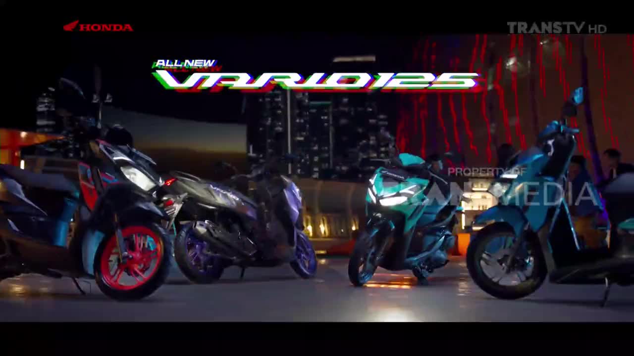 Several new Honda Vario 125 scooters are lined up, illuminated under the "All New Vario 125" logo on Trans TV. The bikes, in various colors, are staged against a backdrop of city lights.
Several new Honda Vario 125 scooters are lined up, illuminated under the "All New Vario 125" logo on Trans TV. The bikes, in various colors, are staged against a backdrop of city lights.