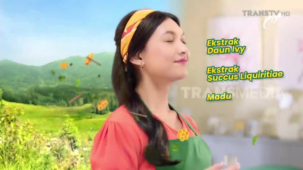 A woman with a yellow bandana breathes deeply, eyes closed, in front of a rolling green landscape. Small, brown and green shapes float around her, suggesting ingredients from the Trans TV advertisement.