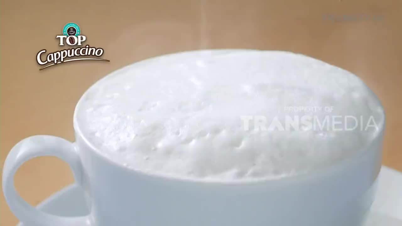 A thick layer of frothy milk crowns a white cup of cappuccino. Wisps of steam rise from the warm drink, hinting at the fresh brew.