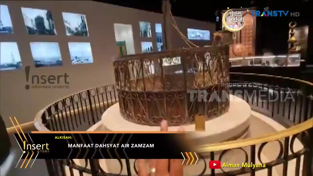 A decorative wellhead, likely a replica of the Zamzam well, stands at the center of a display. The Trans TV logo is visible in the background, suggesting this is from a broadcast in Indonesia.