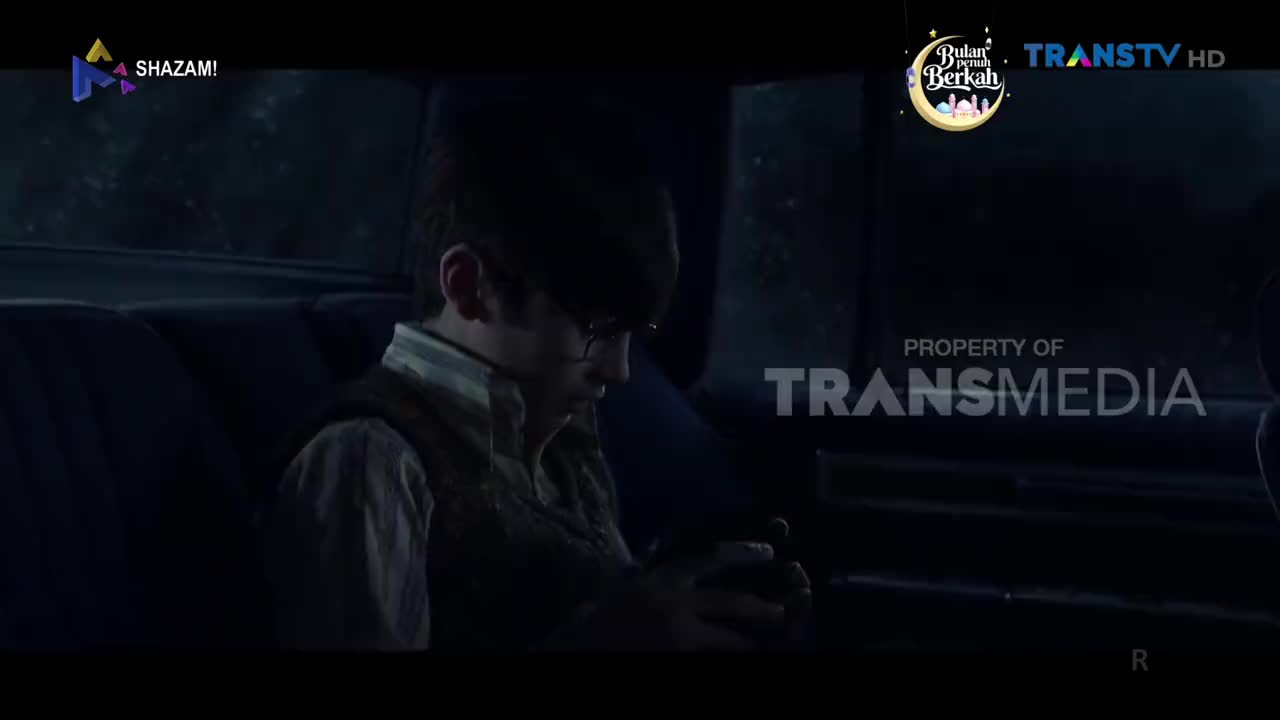 A young boy sits in the back of a car, his head bowed. The Trans TV logo appears in the corner, hinting at a broadcast from Indonesia.