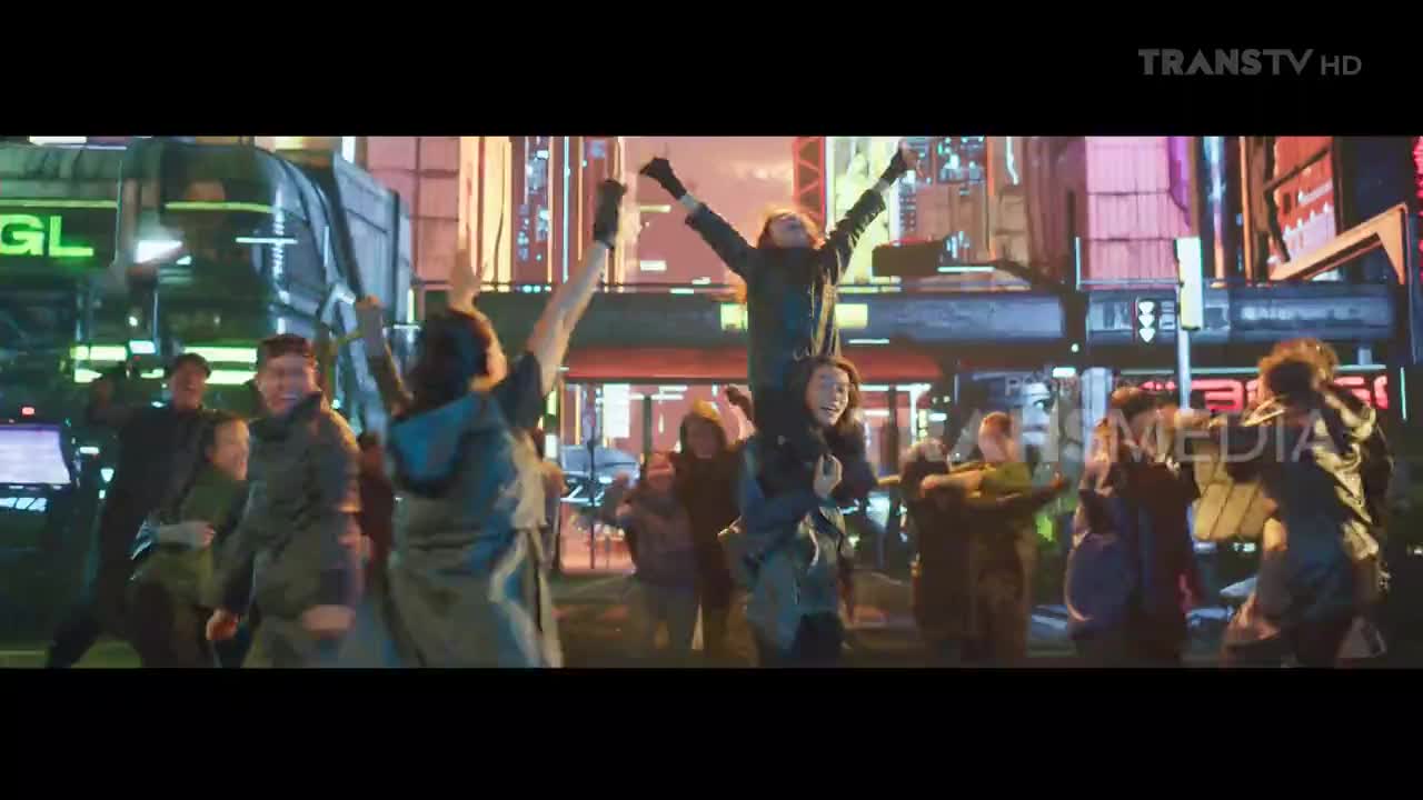 A crowd surges forward under the glow of neon signs, their arms raised in celebration. One person rides on another's shoulders, cheering with infectious energy.