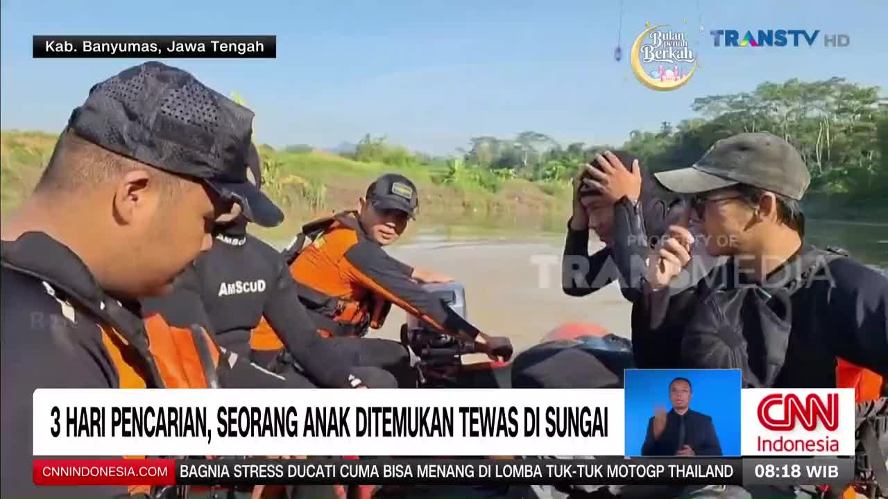 A small boat carrying rescue personnel navigates a wide, calm river under a bright sky. One man in an orange vest checks equipment while another, with his hands on his head, looks distressed.