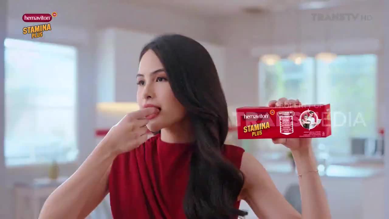 A woman in a red dress brings her finger to her lips while holding a box of Hemaviton Stamina Plus. The Trans TV logo is visible in the background.