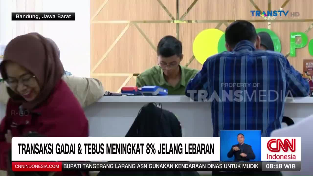 A woman in a maroon hijab laughs as she leans over a counter. Behind her, a man in a blue plaid shirt faces away from the camera, and another man in a green shirt is bent over a transaction machine.