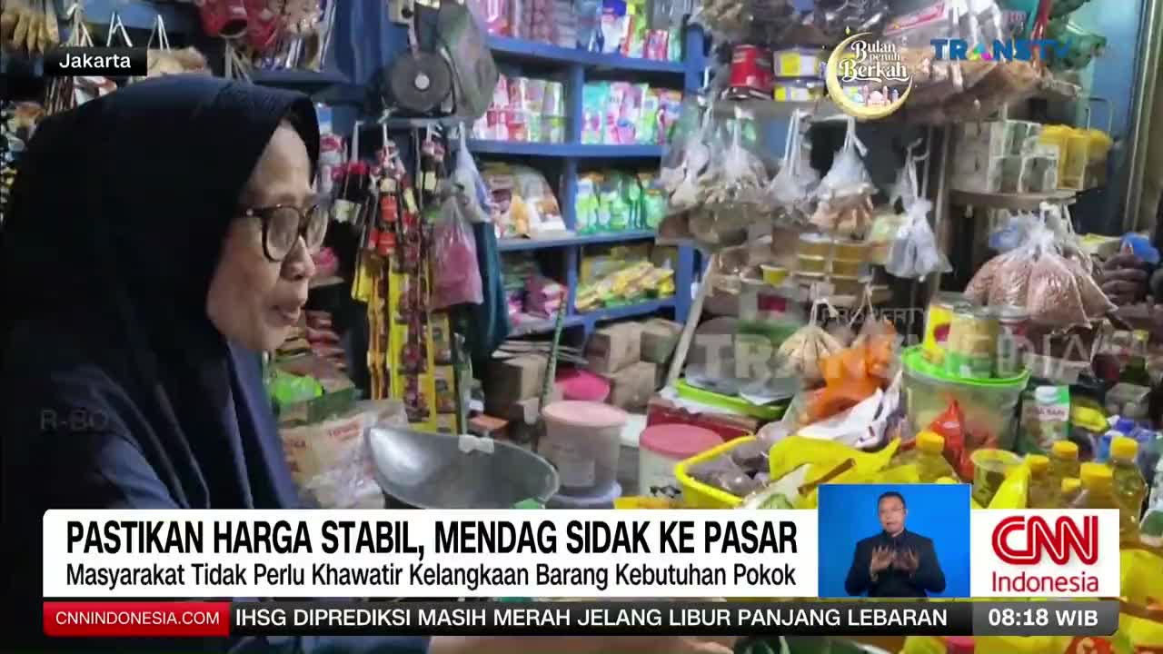 A woman in a hijab speaks at a market stall, surrounded by shelves packed with goods. Behind her, a Trans TV graphic overlays the scene, indicating a news report from Indonesia.