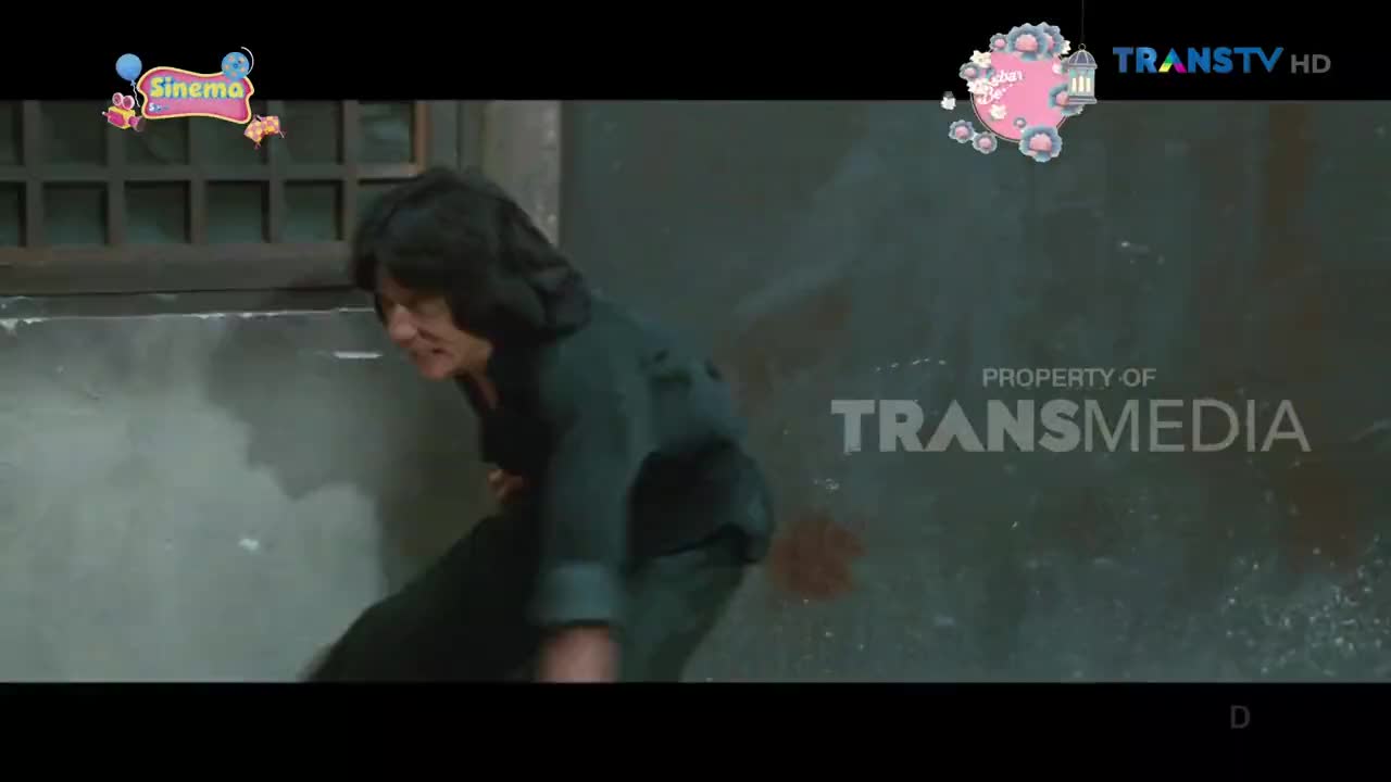 A man with dark hair lunges forward, his face contorted in pain. Dust billows around his feet as he moves against a grimy wall.