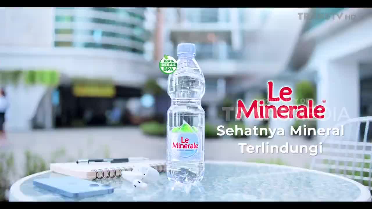 A bottle of Le Minerale stands on a table, its label clearly visible. The Trans TV logo appears in the background, suggesting this is a commercial playing on Indonesian television.