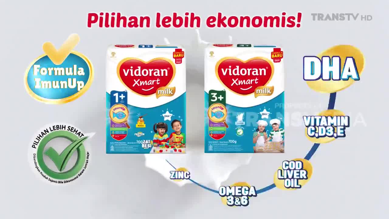 Two boxes of Vidora Xmart milk stand side-by-side, with colorful graphics highlighting their nutritional benefits. A Trans TV HD logo appears in the corner.