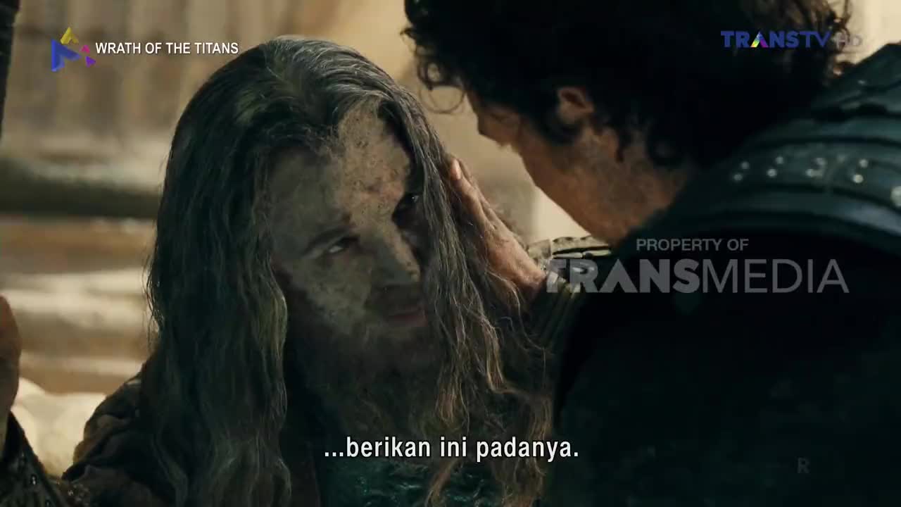 A man with long, dirty hair and a weathered face looks intently at another man, whose hand rests on his forehead. The Trans TV logo is visible in the corner, indicating this scene is part of a broadcast in Indonesia.