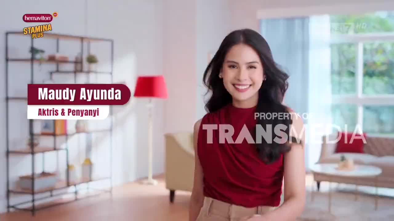 Maudy Ayunda smiles directly at the camera, her image superimposed over a modern living room setting. The "Trans7" logo is visible, indicating a commercial for a stamina product.
