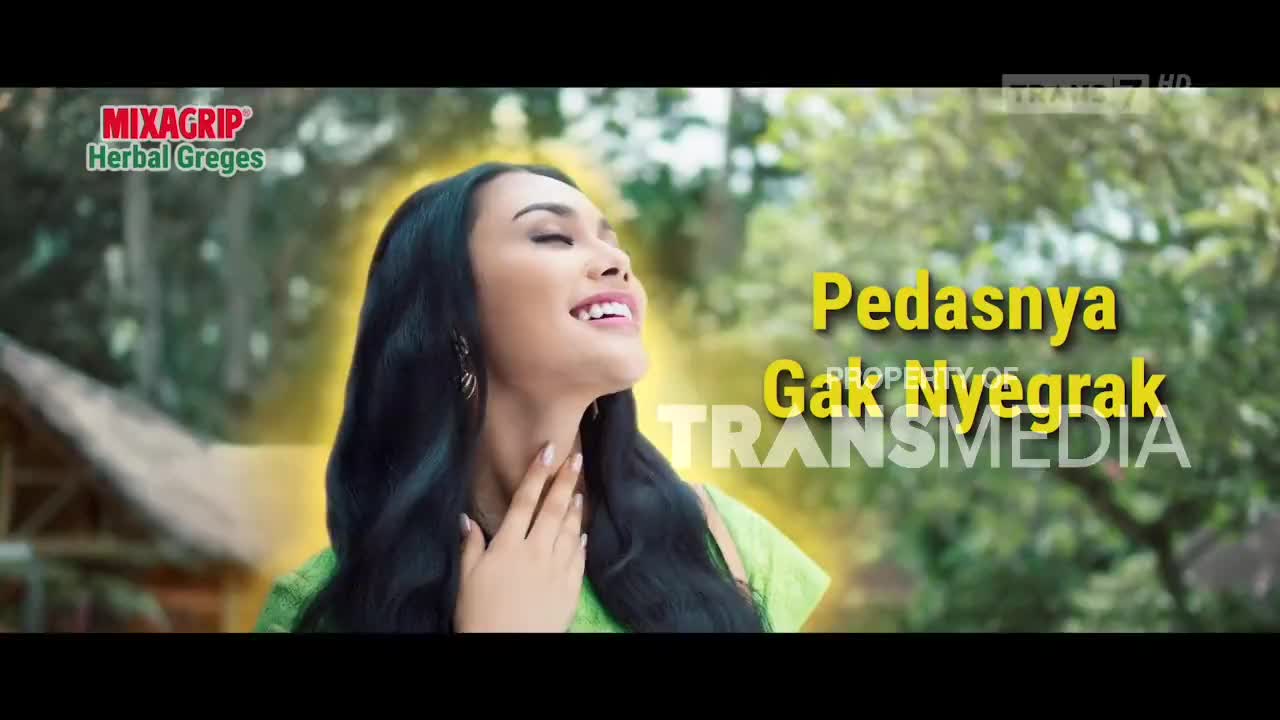 A woman with long, dark hair and a green top smiles, looking upwards. The Trans7 logo and Indonesian text are overlaid on the image.
