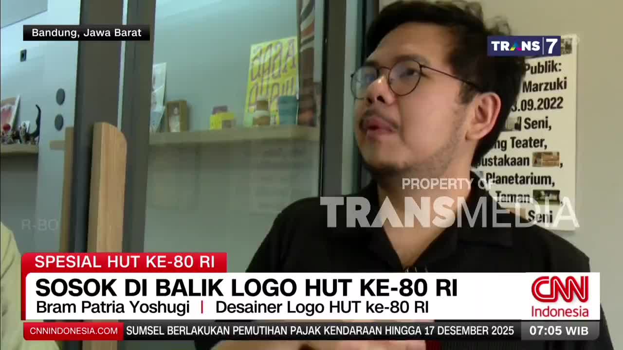 A man in glasses is speaking on a Trans7 television segment, likely in Bandung, West Java. The chyron identifies him as the designer of the logo for the 80th anniversary of the Republic of Indonesia.
