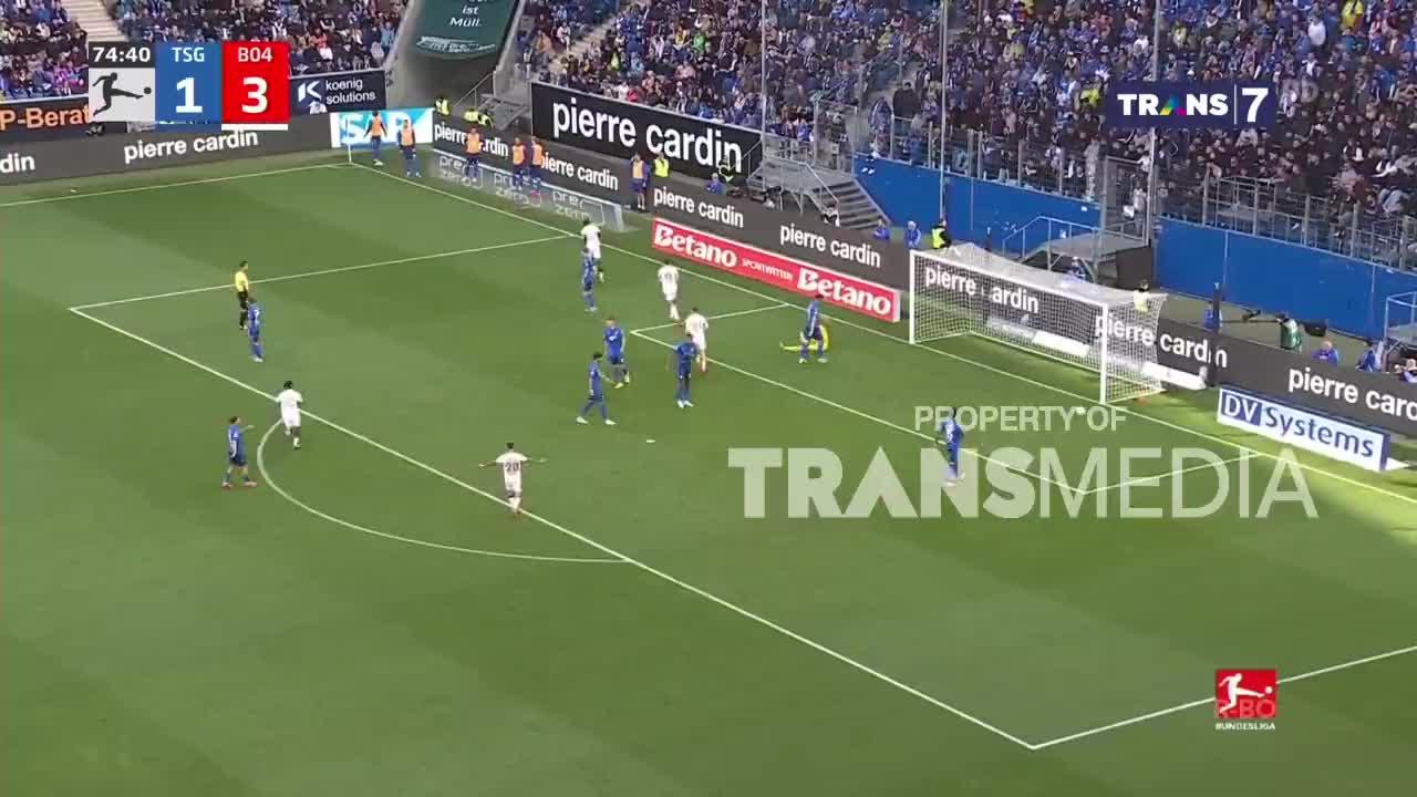 Players in blue and white jerseys are positioned on the pitch, with the score displayed on the screen. The broadcast is brought to you by Trans7.
