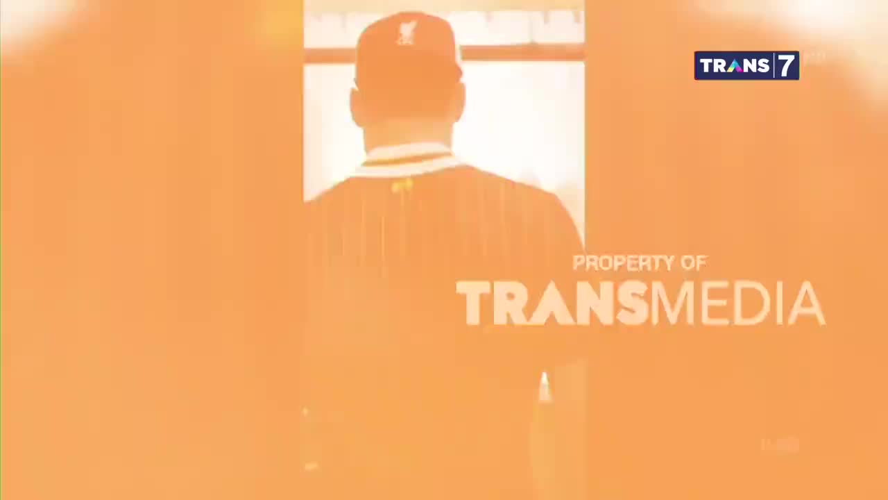 A man in a baseball cap and jersey stands in a doorway, his back to the camera. The Trans7 logo is visible in the corner, along with the Transmedia property notice.
