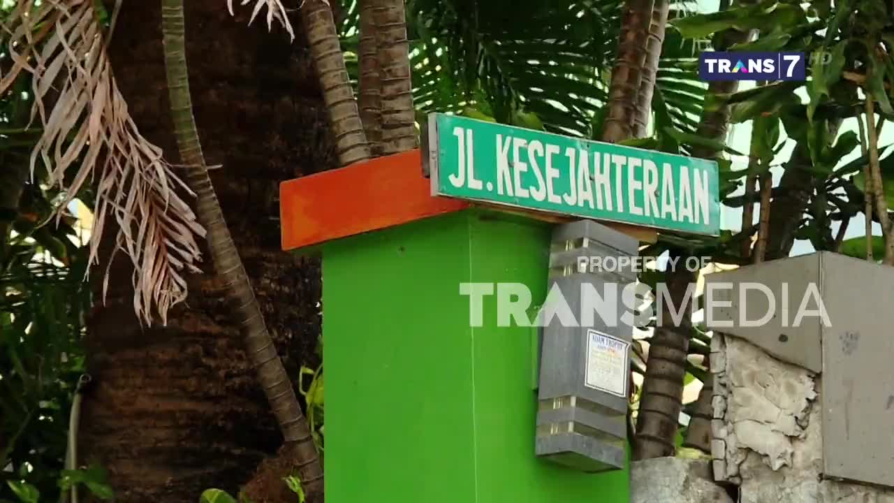 A green street sign reading "Jl. Kesejahteraan" sits above a green pillar. The Trans7 logo is visible, indicating this is likely a broadcast from Indonesia.

