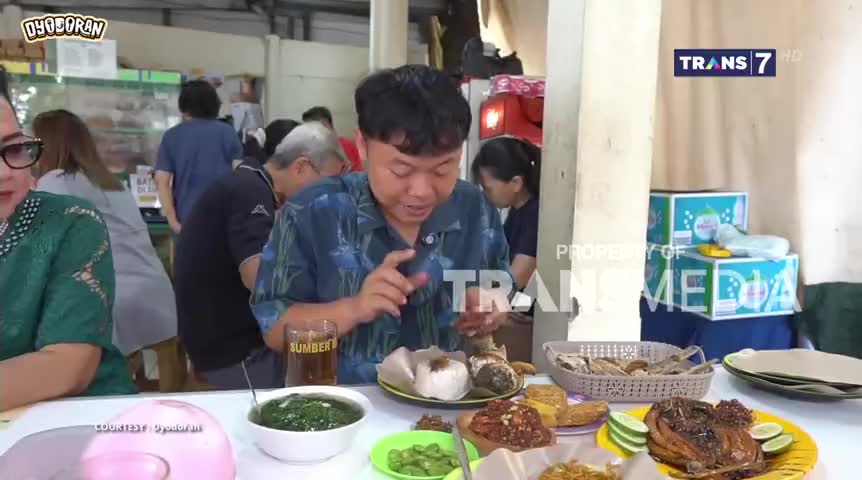 A man in a blue shirt examines a plate of food, seemingly about to take a bite. The scene unfolds in a crowded Indonesian eatery, as a Trans7 logo subtly appears in the corner.
A man in a blue shirt examines a plate of food, seemingly about to take a bite. The scene unfolds in a crowded Indonesian eatery, as a Trans7 logo subtly appears in the corner.
