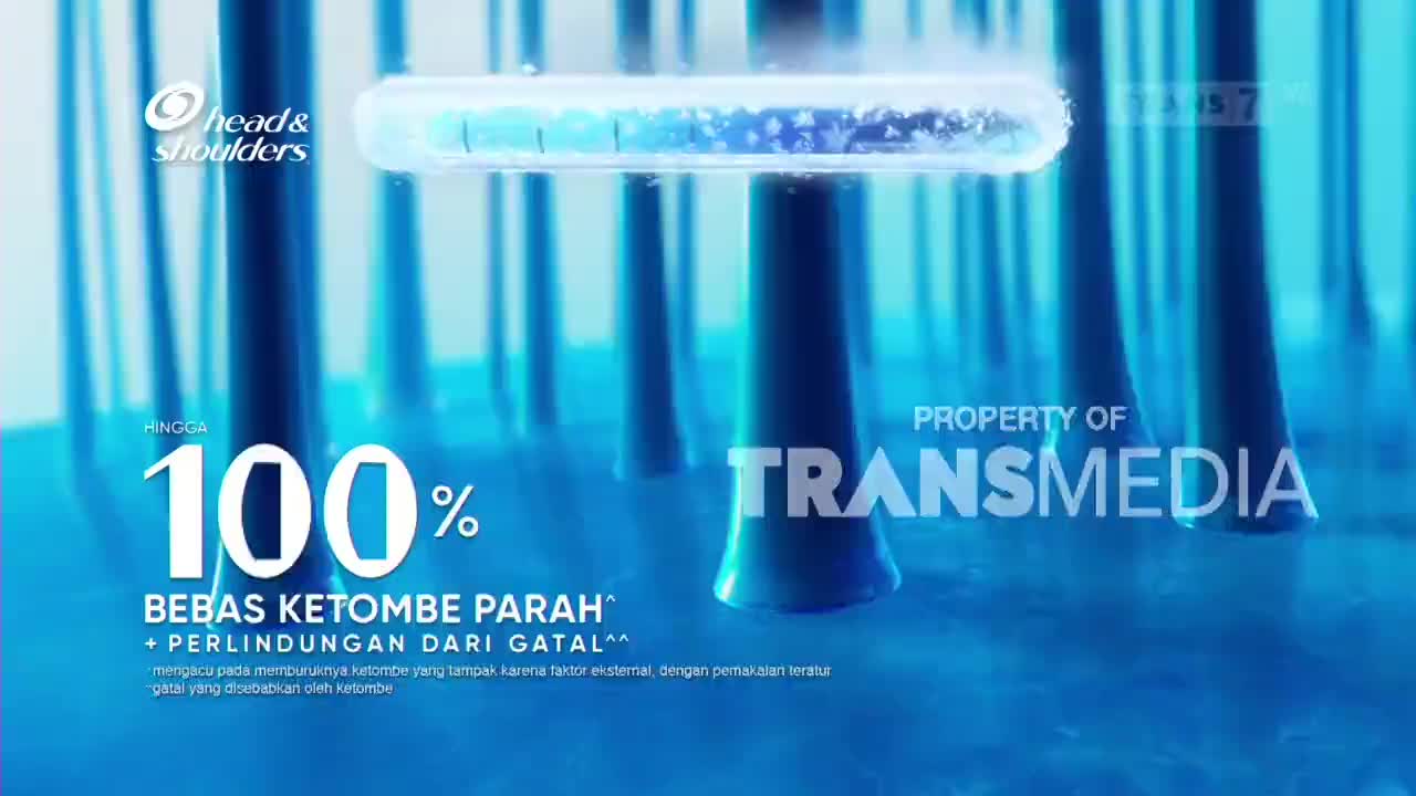 A bright blue liquid flows through a clear tube above dark, upright strands. The Head & Shoulders logo appears on the left, with "100%" and Indonesian text below.
