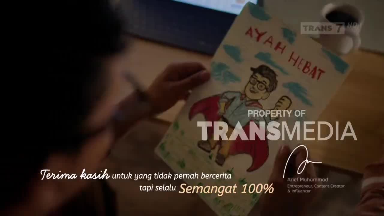 A child's drawing of a superhero dad, titled "Ayah Hebat," is held up. Trans7's logo is visible in the background, alongside a handwritten message in Indonesian.
