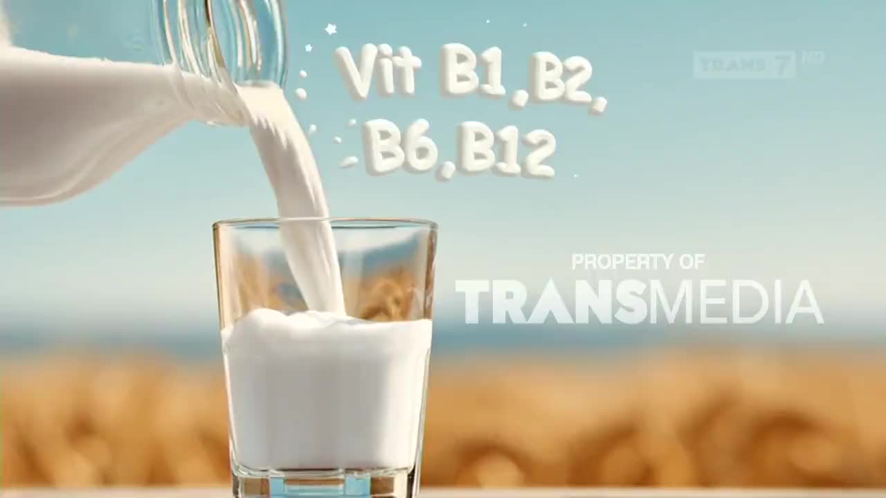 White milk streams from a glass bottle into a clear glass, creating a frothy head. The Transmedia logo appears in the background, hinting at the broadcast on Trans7.