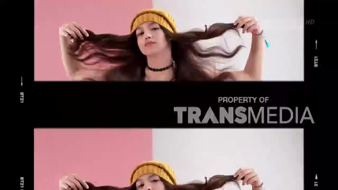 A young woman with a yellow beanie and long, dark hair plays with her strands, letting them fall around her face. The Transmedia logo appears across the middle of the screen, indicating this is likely a segment from a Trans7 broadcast in Indonesia.