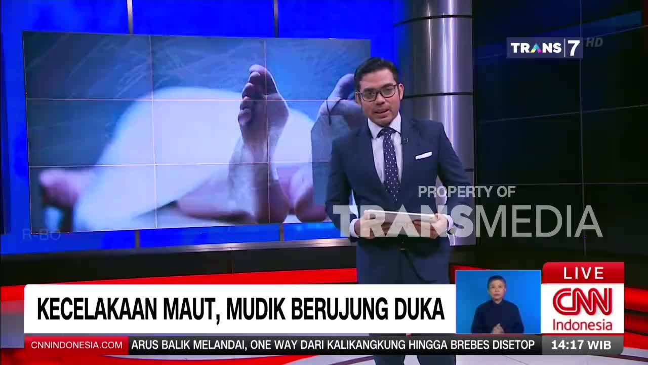A news anchor stands in front of a screen displaying a close-up of feet, likely related to a fatal accident report on Trans7. The text below the screen reads "KEcelakaan Maut, Mudik Berujung Duka," which translates to "Fatal Accident, Homecoming Ends in Sorrow."