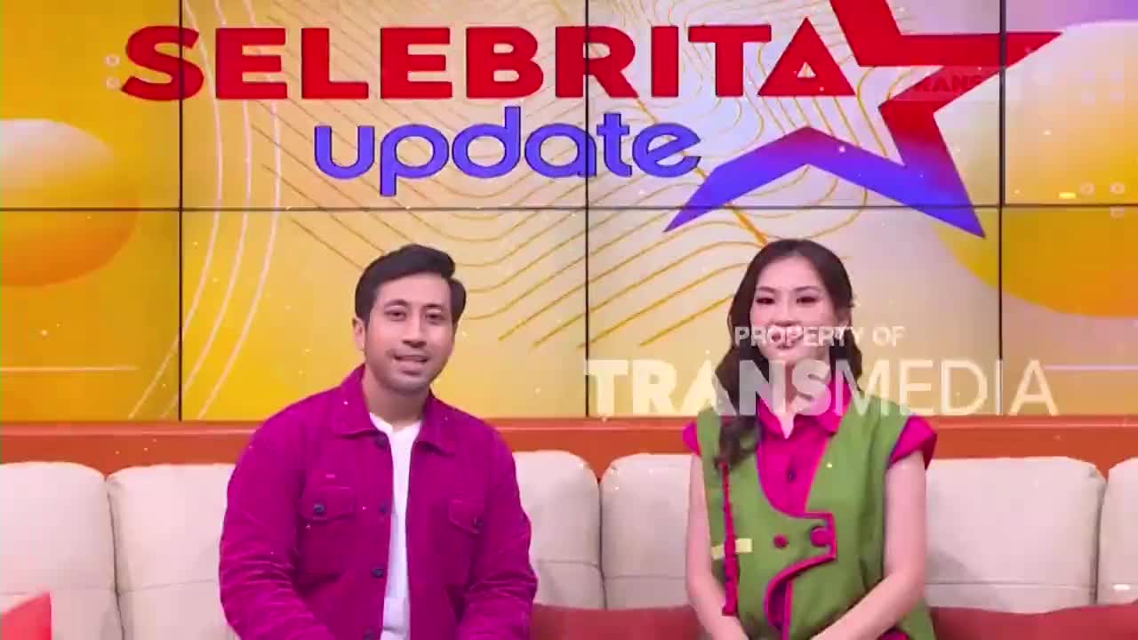 Two presenters sit on a couch, bathed in the bright lights of a studio. The Trans7 logo is visible behind them, beneath a screen displaying "Selebrita Update."