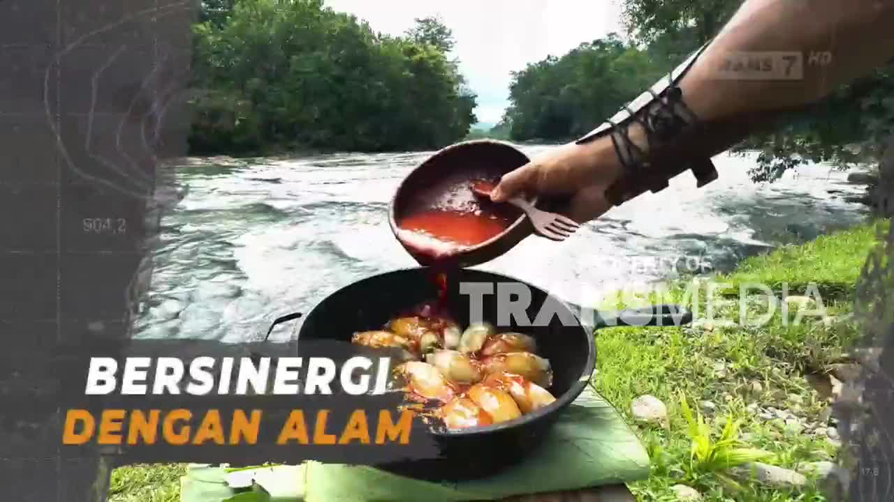 A hand pours a rich, red sauce over what looks like fried food in a pan, right beside a fast-flowing river. The Trans7 logo is visible, hinting at a travel or culinary show.