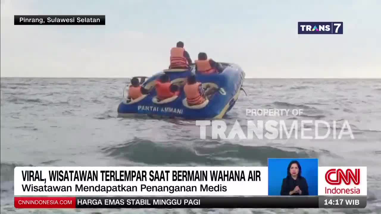 A blue inflatable raft with several people wearing life vests bobs on choppy water off the coast of Pinrang, Sulawesi Selatan. The raft, labeled "Pantai Ammani," appears to have just tipped, with some passengers still seated and others leaning precariously. A blue inflatable raft with several people wearing life vests bobs on choppy water off the coast of Pinrang, Sulawesi Selatan. The raft, labeled "Pantai Ammani," appears to have just tipped, with some passengers still seated and others leaning precariously.