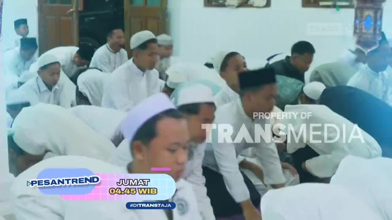 A group of men in white attire are bowing their heads in prayer. The Trans7 logo is visible in the background, indicating this is a broadcast from Indonesia.