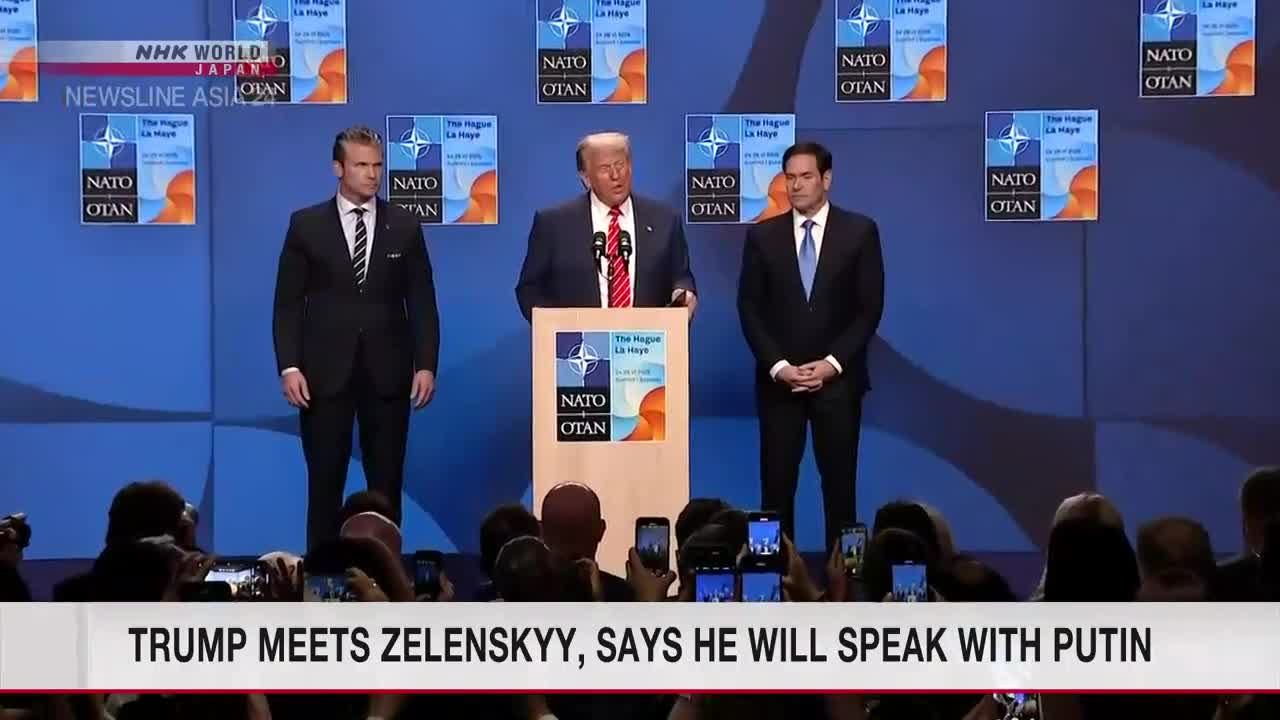 From the NHK World-Japan broadcast, Donald Trump stands at a podium, speaking into microphones, flanked by two men in suits. The audience below is holding up phones, capturing the scene.
