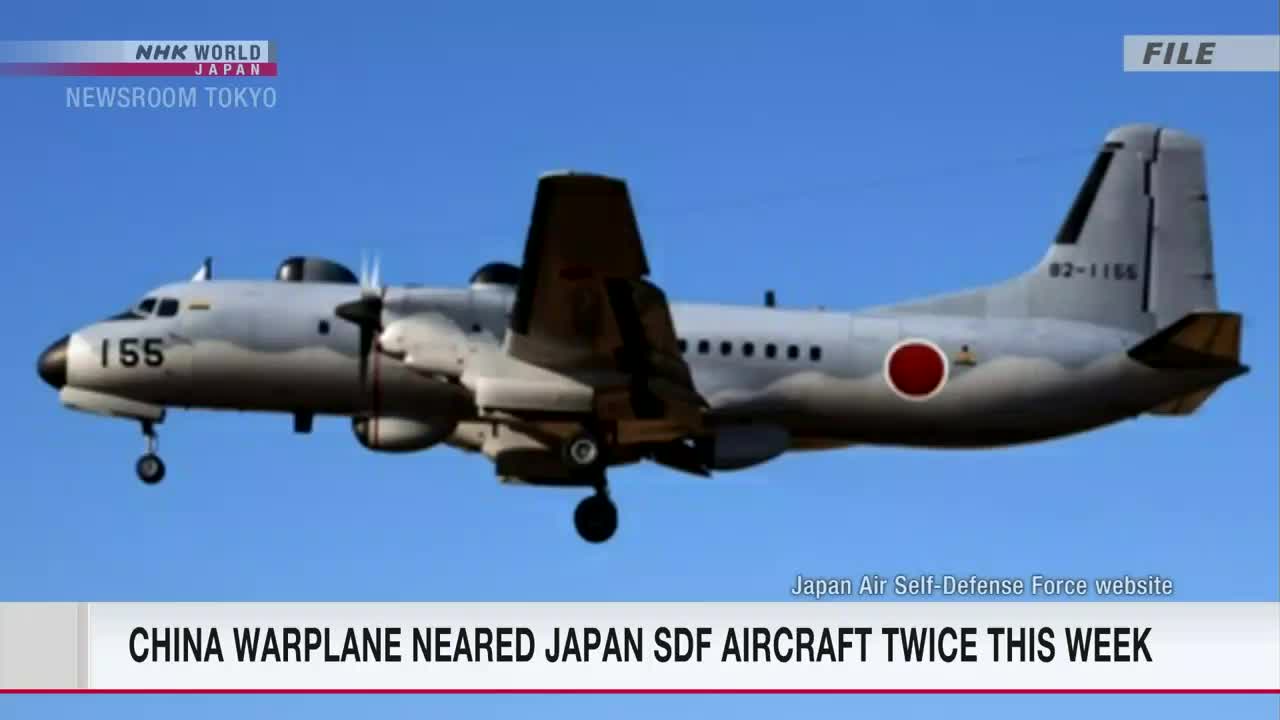A Japanese Self-Defense Force aircraft, marked with the red circle of Japan, is airborne against a clear blue sky. The NHK World-Japan Newsroom Tokyo graphic anchors the scene.

