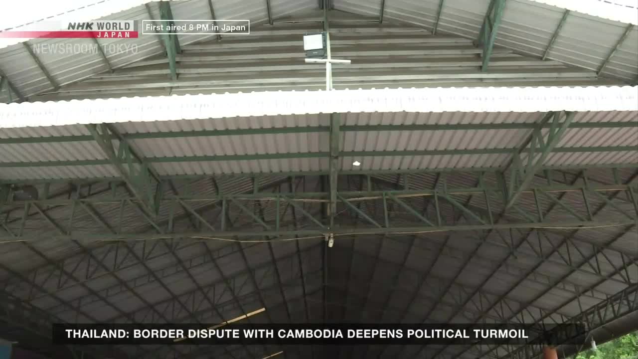 Above, a metal-framed roof stretches out, its corrugated panels reflecting the light. The NHK World-Japan broadcast from Tokyo is reporting on a border dispute, as the camera focuses on the structure.
