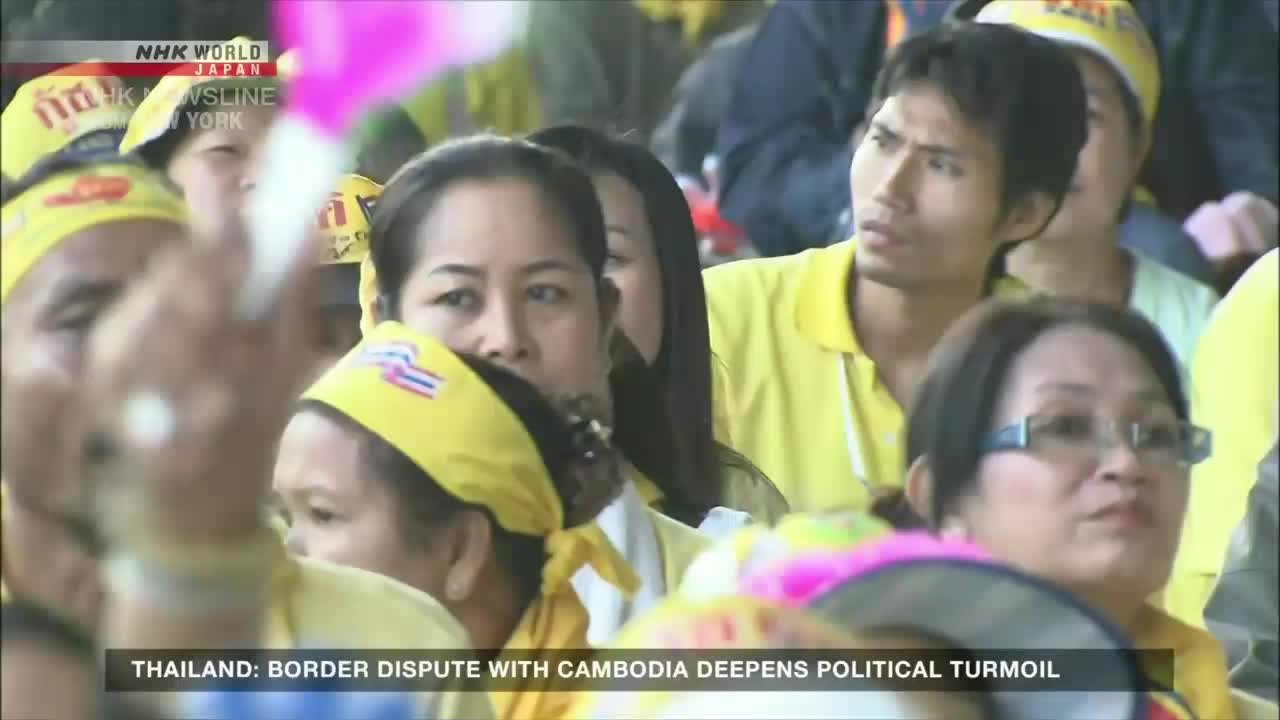 People in yellow shirts and headbands are packed together, many with their eyes fixed on something beyond the frame. The NHK World-Japan news report from New York is covering a story about political turmoil in Thailand.
