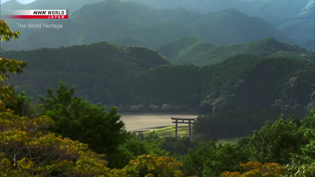 The NHK World-Japan logo sits in the corner, framing a view of the Japanese countryside. A torii gate stands in the distance, framed by rolling green hills.
