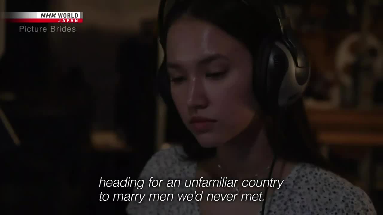 A young woman with headphones sits in a dimly lit room, her gaze downcast. Text on the screen from NHK World-Japan, "Picture Brides," hints at the story's focus.
