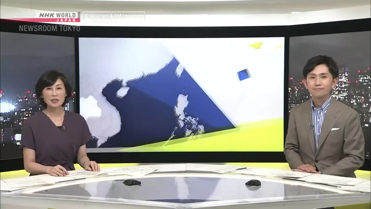Two news anchors sit at a desk in the NHK World-Japan studio in Tokyo. Behind them, a graphic of a map is displayed on a large screen.
