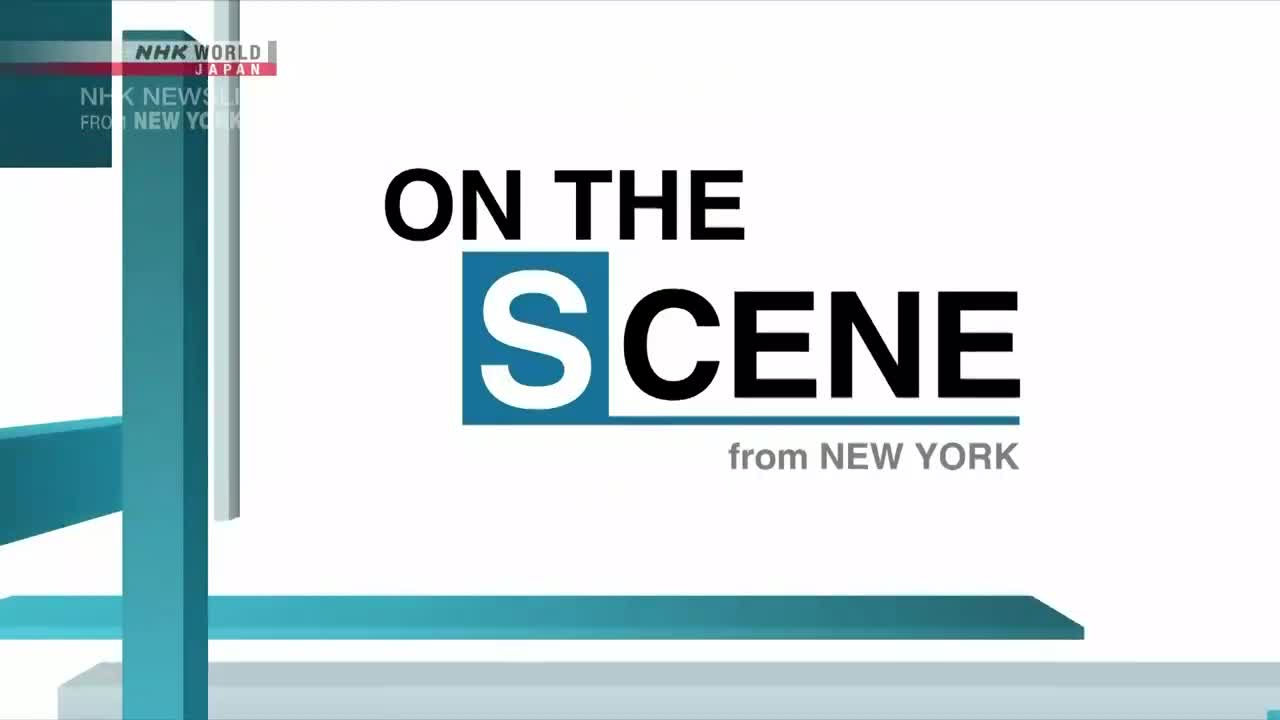 The words "ON THE SCENE" are prominently displayed against a white backdrop, with "S" in a blue box. Below, the text "from NEW YORK" appears, likely part of an NHK World-Japan news segment.
