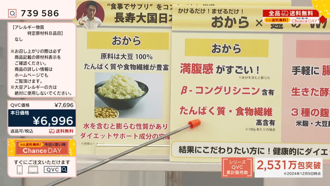 A presenter on QVC Japan points with a red-tipped pointer to a panel describing "okara," a soy product. The screen displays information about the product, including its ingredients, benefits, and a special "Chance Day" price.

