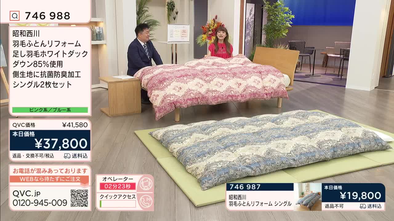 A man and a woman stand beside a bed, demonstrating a patterned duvet on a QVC Japan set.  A second duvet, folded on a mat, is presented below.
