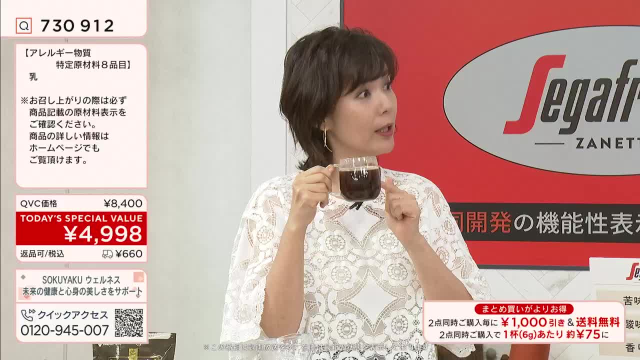 A woman in a lace top holds a glass of dark liquid, likely coffee, while speaking on a QVC-style broadcast. The screen displays a price, in Japanese yen, for a "Today's Special Value" item.
