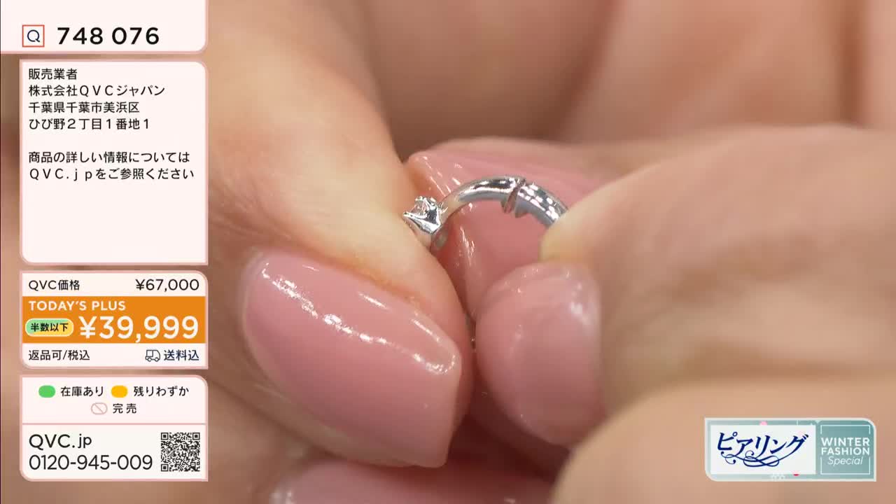 A hand, with perfectly manicured nails, holds a small, silver earring. The clasp is being opened, revealing a tiny, sparkling stone.
