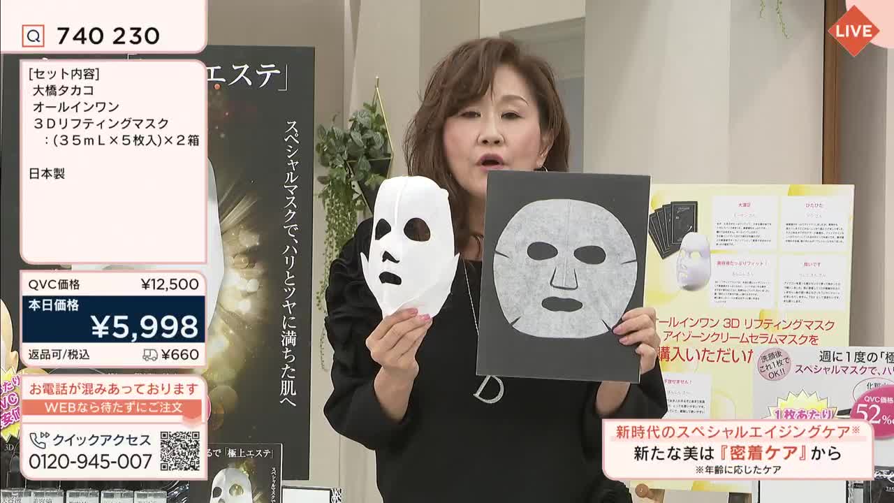A woman on a QVC-style show in Japan holds up a white face mask and a package of similar masks, gesturing towards the camera. The screen displays the product's price and details in Japanese characters.
