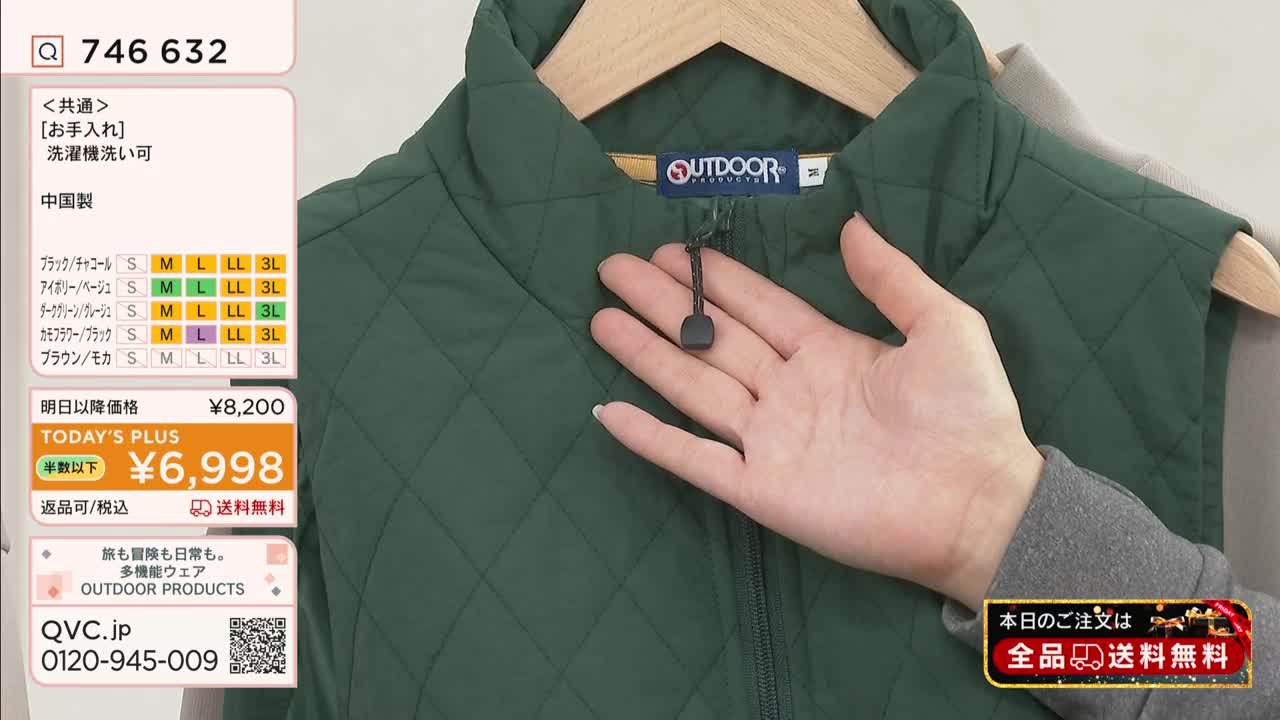A hand gently holds the zipper pull of a quilted green vest, displayed on a wooden hanger. A QVC Japan screen displays the price and size options for the garment.
