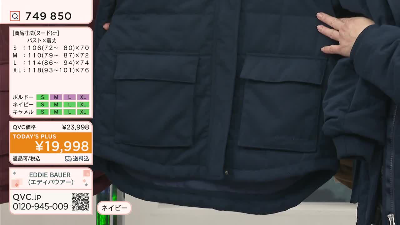 A navy blue Eddie Bauer jacket is being presented on QVC Japan. The presenter's hand is visible as they hold open the front, showing the large pockets.
